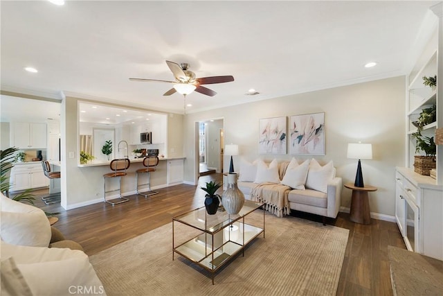 living room with sink, crown molding, light hardwood / wood-style floors, and ceiling fan