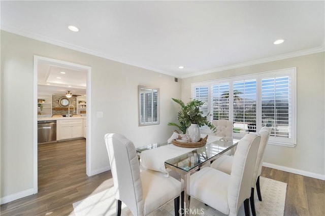 dining area with hardwood / wood-style flooring, crown molding, and sink