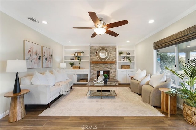 living room with ornamental molding, a large fireplace, ceiling fan, and light wood-type flooring