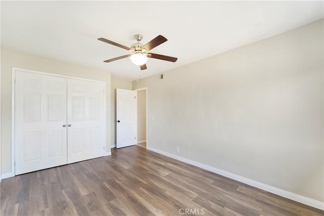 unfurnished bedroom with dark wood-type flooring, ceiling fan, and a closet