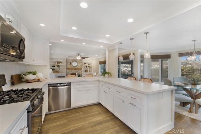 kitchen featuring pendant lighting, white cabinetry, stainless steel appliances, and kitchen peninsula