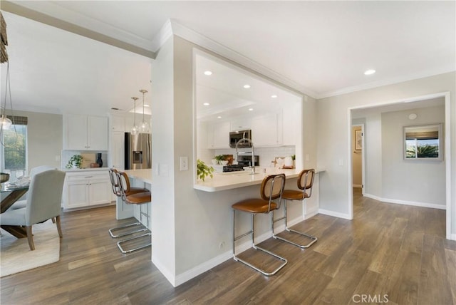 kitchen with decorative light fixtures, a breakfast bar area, white cabinets, kitchen peninsula, and stainless steel appliances