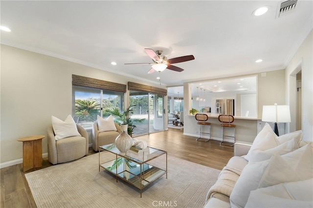 living room featuring crown molding, ceiling fan, and light hardwood / wood-style floors