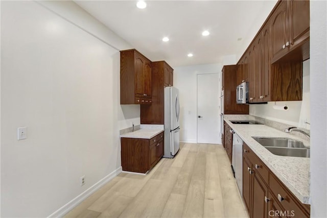 kitchen with sink, fridge, light stone counters, black electric cooktop, and light wood-type flooring