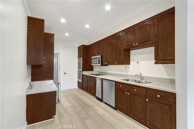 kitchen with stainless steel appliances, sink, and light hardwood / wood-style flooring