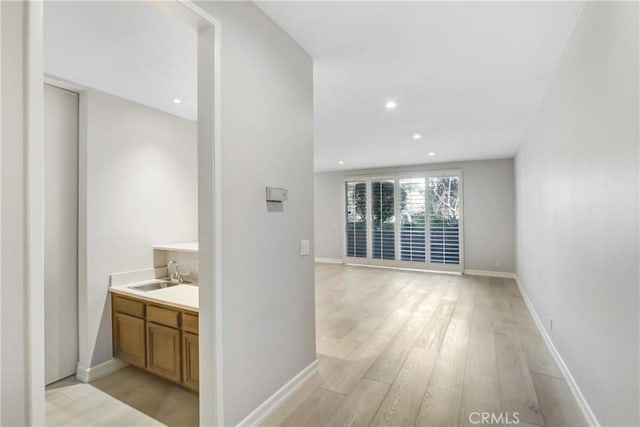 hallway featuring sink and light hardwood / wood-style flooring