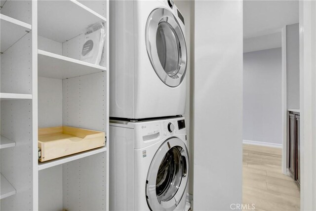 laundry area featuring light hardwood / wood-style floors and stacked washer and clothes dryer