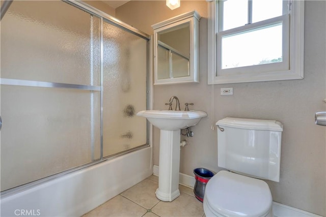 bathroom with tile patterned floors, toilet, and combined bath / shower with glass door