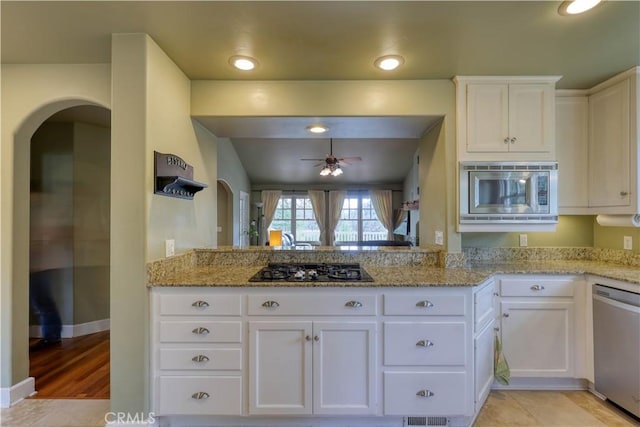 kitchen featuring ceiling fan, stainless steel appliances, light stone countertops, white cabinets, and kitchen peninsula