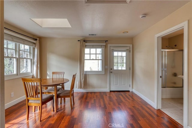 dining area with dark hardwood / wood-style flooring and a skylight