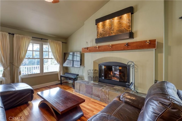 living room featuring hardwood / wood-style flooring, vaulted ceiling, and a tile fireplace