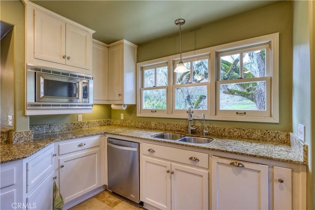 kitchen featuring sink, white cabinetry, light stone counters, pendant lighting, and stainless steel appliances