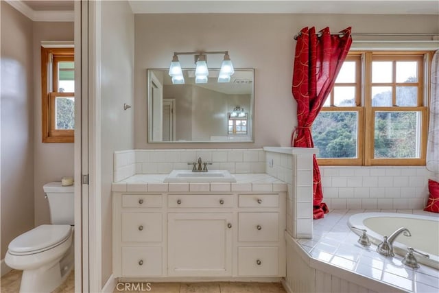 bathroom with vanity, toilet, and tiled bath