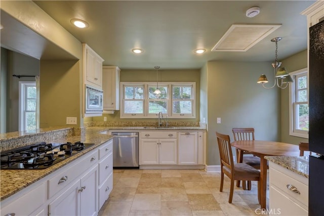 kitchen featuring white cabinetry, sink, stainless steel appliances, and hanging light fixtures