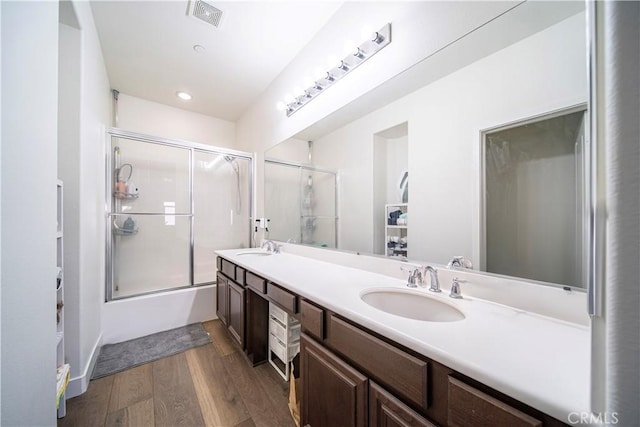 bathroom featuring enclosed tub / shower combo, vanity, and hardwood / wood-style floors