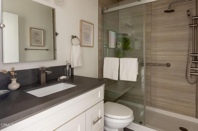 bathroom featuring vanity, an enclosed shower, and toilet