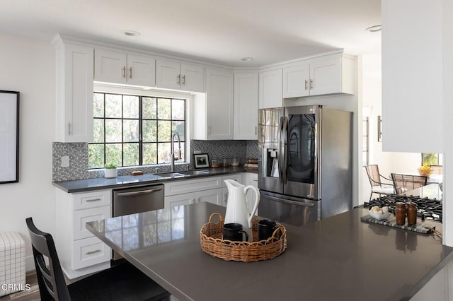 kitchen featuring sink, white cabinetry, appliances with stainless steel finishes, kitchen peninsula, and decorative backsplash