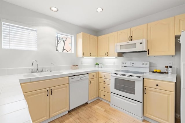 kitchen with light hardwood / wood-style flooring, sink, white appliances, and tile countertops