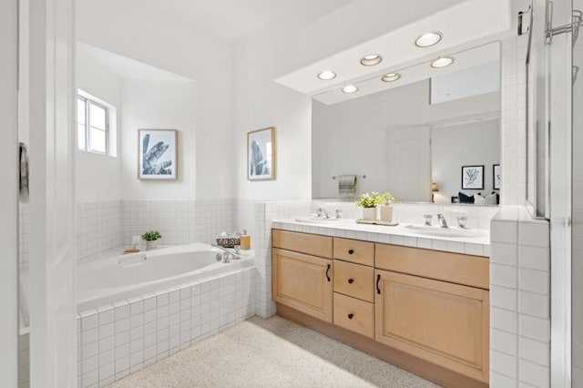 bathroom with vanity and a relaxing tiled tub