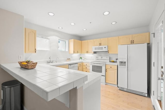 kitchen featuring sink, tile countertops, light brown cabinets, kitchen peninsula, and white appliances