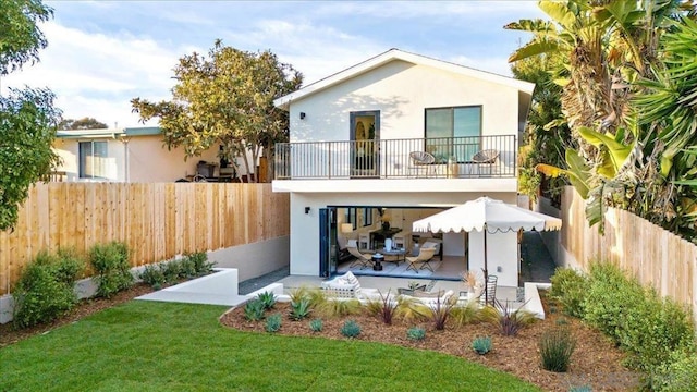 back of house featuring a balcony and a yard