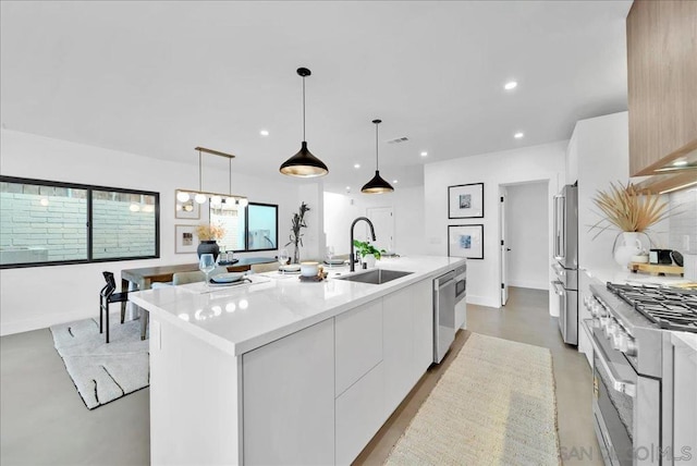 kitchen featuring pendant lighting, sink, a kitchen island with sink, high quality appliances, and white cabinets