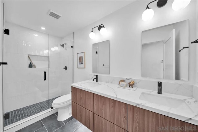 bathroom featuring a shower with door, vanity, tile patterned floors, and toilet