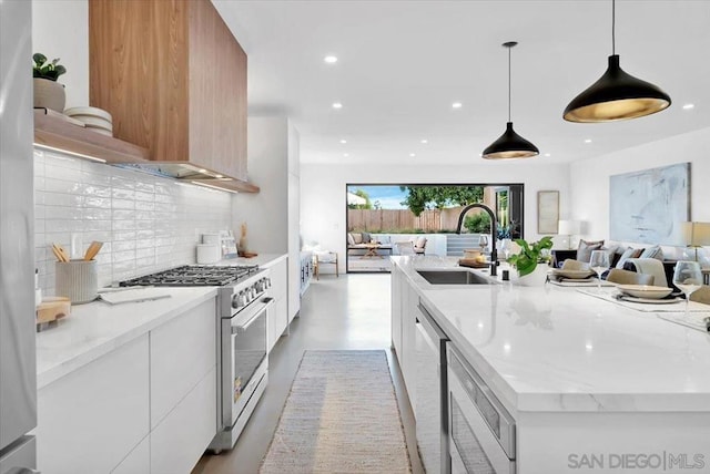 kitchen with sink, white cabinetry, decorative light fixtures, high end stainless steel range oven, and light stone countertops