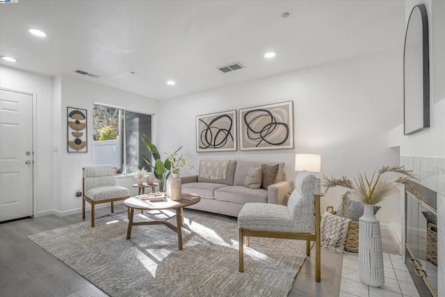 living room with a tile fireplace and light wood-type flooring