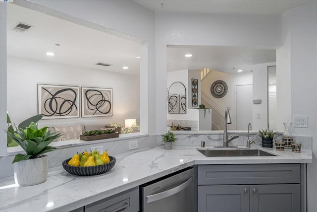 kitchen with dishwasher, light stone countertops, sink, and gray cabinetry