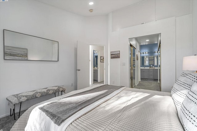 bedroom with connected bathroom, carpet flooring, and a high ceiling