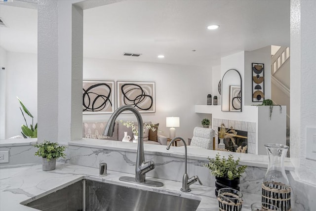 kitchen featuring sink, light stone counters, and a fireplace