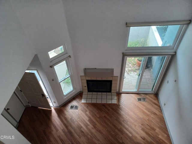 unfurnished living room featuring a high ceiling, dark hardwood / wood-style flooring, a healthy amount of sunlight, and a fireplace