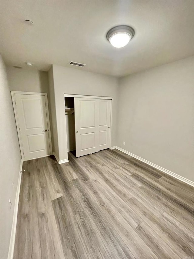 unfurnished bedroom with light hardwood / wood-style flooring and a closet