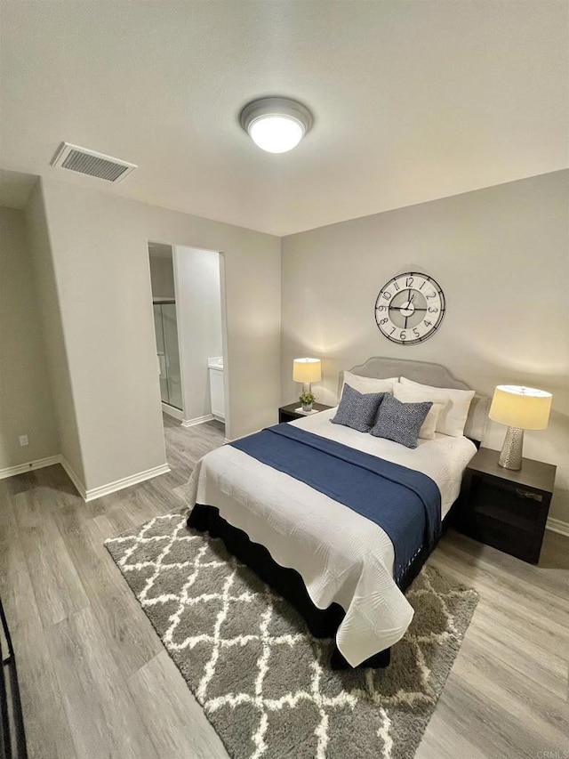 bedroom with ensuite bath and wood-type flooring