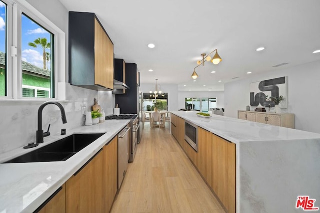 kitchen featuring sink, stainless steel dishwasher, light stone counters, and light hardwood / wood-style floors