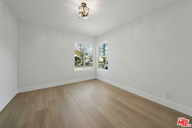 empty room featuring an inviting chandelier and light hardwood / wood-style floors