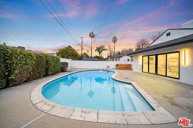 pool at dusk featuring a patio area