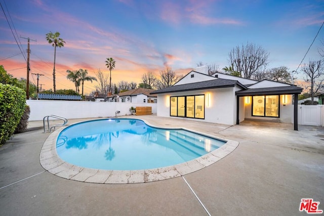 pool at dusk with a patio