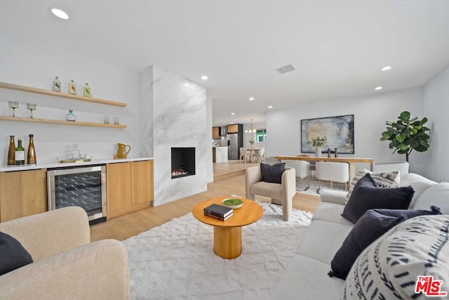 living room featuring bar area, wine cooler, light wood-type flooring, and a fireplace