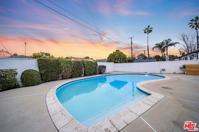 pool at dusk featuring a patio area