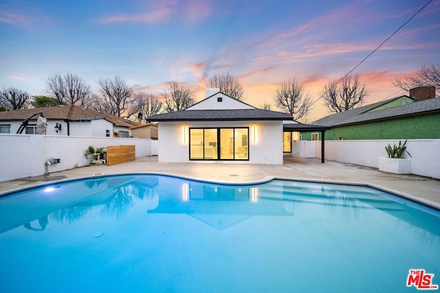 pool at dusk with a patio