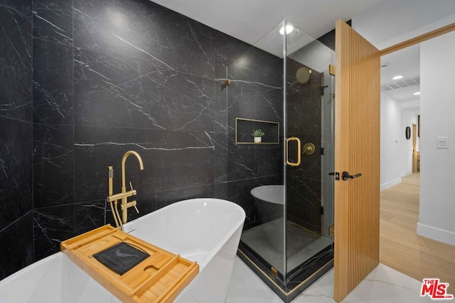 bathroom with shower with separate bathtub, hardwood / wood-style floors, and tile walls