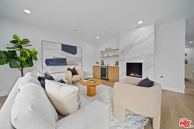 living room featuring bar area, wine cooler, a fireplace, and light hardwood / wood-style flooring