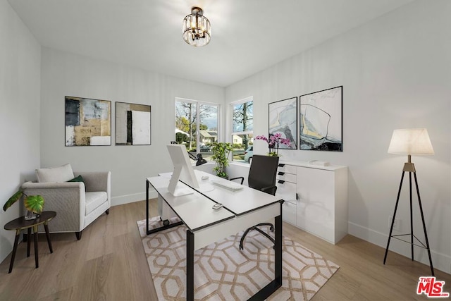 home office featuring an inviting chandelier and light hardwood / wood-style floors