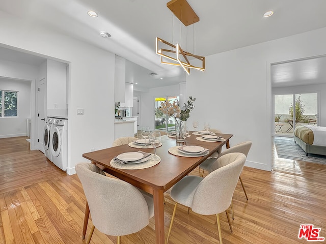 dining room with a chandelier, plenty of natural light, washer and clothes dryer, and light hardwood / wood-style floors