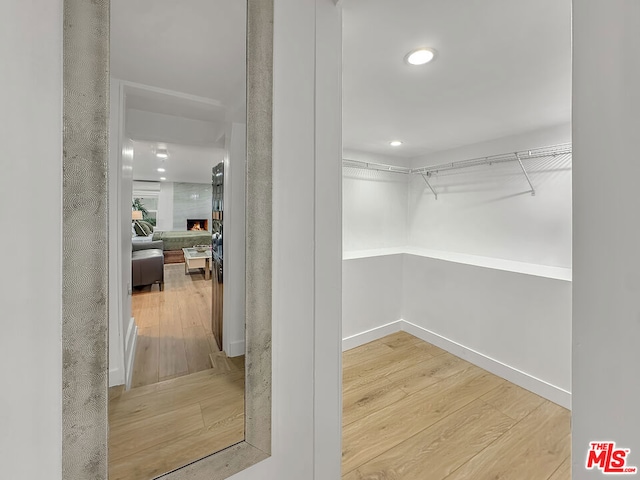 walk in closet with wood-type flooring and a large fireplace