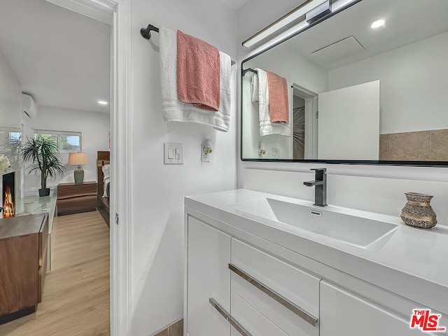 bathroom with wood-type flooring, a wall mounted air conditioner, and vanity