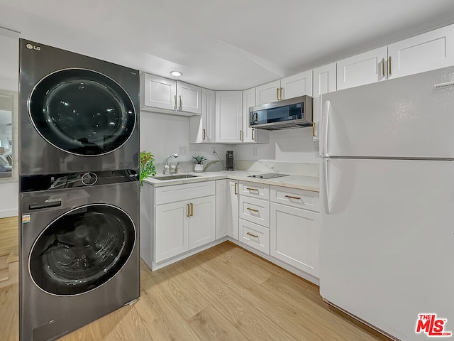 laundry area with stacked washer and dryer, sink, and light wood-type flooring