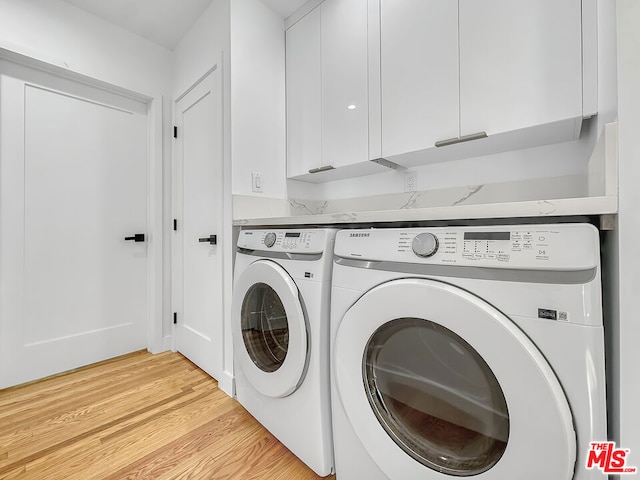 washroom featuring cabinets, washer and clothes dryer, and light wood-type flooring